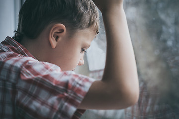 Image showing portrait one sad little boy sitting near a window