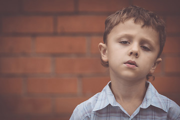 Image showing portrait one sad little boy standing near a wall