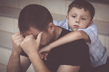 Image showing Portrait of young sad little boy and father sitting outdoors at 