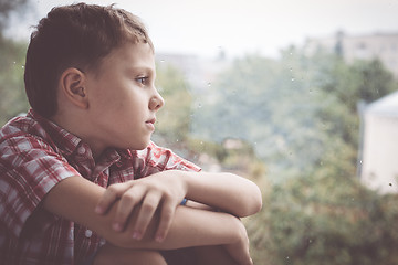 Image showing portrait one sad little boy sitting near a window