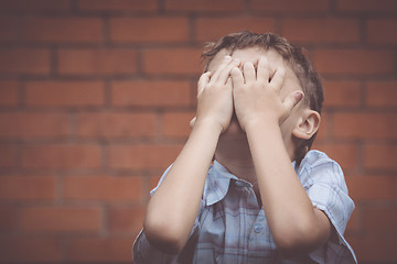 Image showing portrait one sad little boy standing near a wall