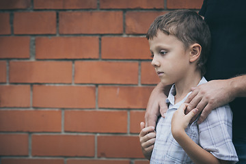 Image showing Portrait of young sad little boy and father standing outdoors at