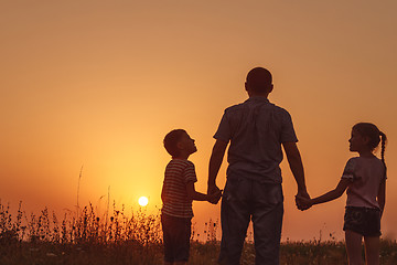 Image showing Father and children standing in the park at the sunset time. 