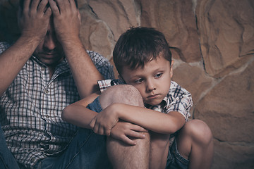 Image showing Portrait of young sad little boy and father sitting outdoors at 