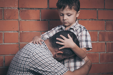 Image showing Portrait of young sad little boy and father sitting outdoors at 