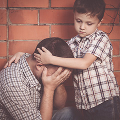 Image showing Portrait of young sad little boy and father sitting outdoors at 