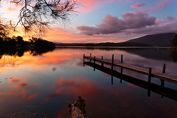 Image showing Scenic sunset and reflections on lake with old jetty 
