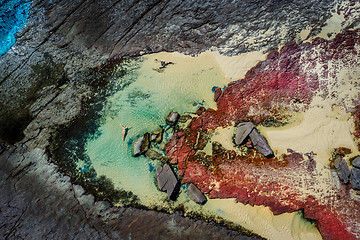 Image showing Floating in pretty blue tidal pools, red and grey rocks, creamy 