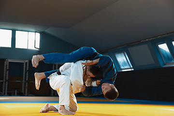 Image showing Two young judo fighters in kimono training martial arts in the gym with expression, in action and motion