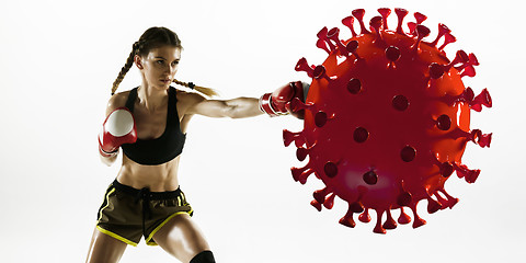 Image showing Professional sportswoman kicking, punching coronavirus model - fight the desease, flyer
