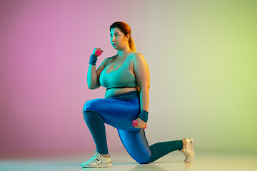 Image showing Young caucasian plus size female model\'s training on gradient purple green background