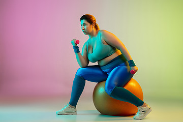 Image showing Young caucasian plus size female model\'s training on gradient purple green background