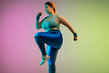 Image showing Young caucasian plus size female model\'s training on gradient purple green background