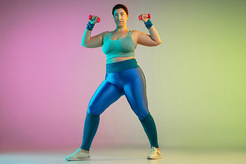 Image showing Young caucasian plus size female model\'s training on gradient purple green background