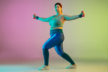 Image showing Young caucasian plus size female model\'s training on gradient purple green background