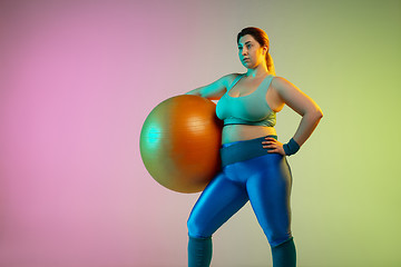 Image showing Young caucasian plus size female model\'s training on gradient purple green background