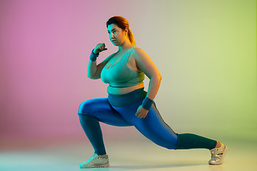 Image showing Young caucasian plus size female model\'s training on gradient purple green background