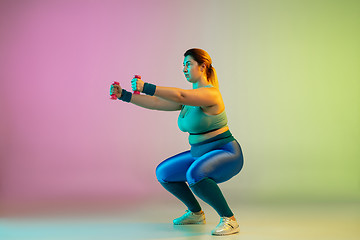 Image showing Young caucasian plus size female model\'s training on gradient purple green background