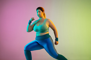 Image showing Young caucasian plus size female model\'s training on gradient purple green background