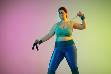 Image showing Young caucasian plus size female model\'s training on gradient purple green background