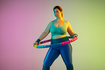 Image showing Young caucasian plus size female model\'s training on gradient purple green background