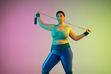 Image showing Young caucasian plus size female model\'s training on gradient purple green background