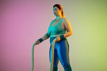 Image showing Young caucasian plus size female model\'s training on gradient purple green background