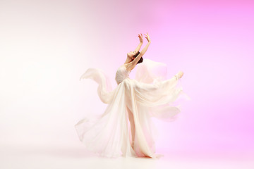 Image showing Ballerina. Young graceful female ballet dancer dancing over pink studio. Beauty of classic ballet.