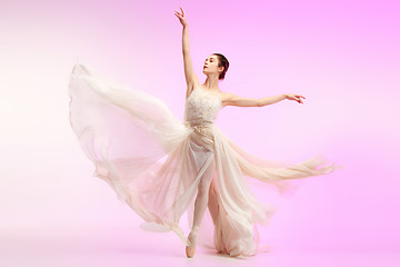 Image showing Ballerina. Young graceful female ballet dancer dancing over pink studio. Beauty of classic ballet.