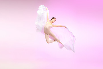 Image showing Ballerina. Young graceful female ballet dancer dancing over pink studio. Beauty of classic ballet.