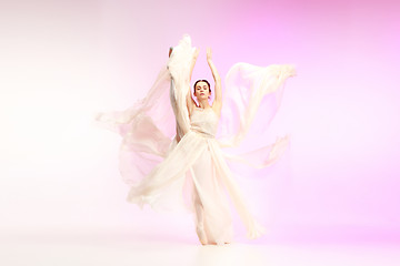 Image showing Ballerina. Young graceful female ballet dancer dancing over pink studio. Beauty of classic ballet.