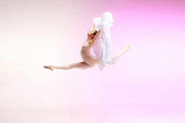 Image showing Ballerina. Young graceful female ballet dancer dancing over pink studio. Beauty of classic ballet.