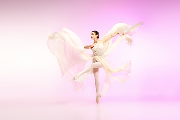 Image showing Ballerina. Young graceful female ballet dancer dancing over pink studio. Beauty of classic ballet.