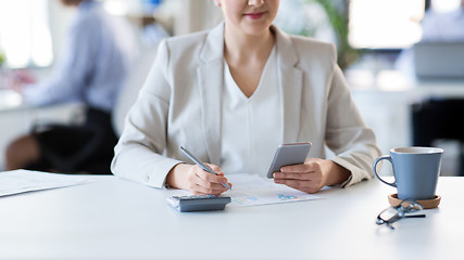 Image showing businesswoman with smartphone working at office