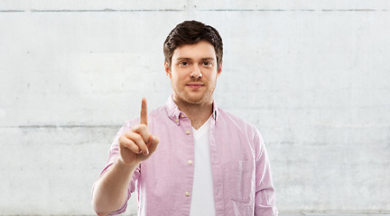 Image showing young man showing one finger over grey background