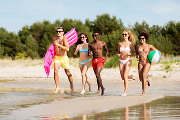 Image showing friends run with beach ball and swimming mattress