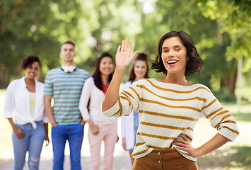 Image showing smiling woman waving hand over summer park