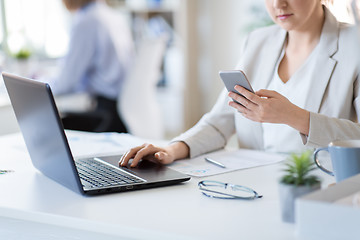 Image showing businesswoman with smartphone and laptop at office