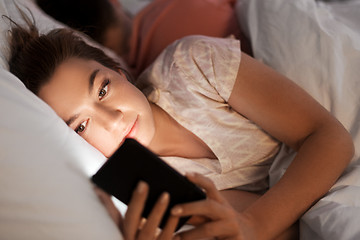 Image showing woman using smartphone while boyfriend is sleeping