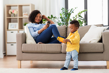 Image showing baby playing toy car and mother with smartphone