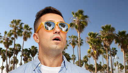 Image showing surprised man in sunglasses over palm trees