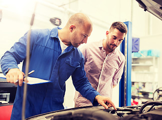 Image showing auto mechanic with clipboard and man at car shop