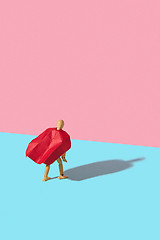 Image showing Wooden mannequin model in a red cape as a superhero with shadow.