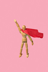 Image showing Wooden mannequin miniature doll in a red cape flies up as a superman.