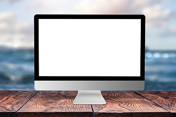 Image showing Mock-up computer display on wooden table against sea background.