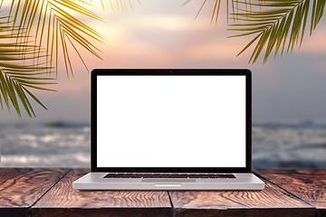 Image showing Laptop mockup screen on wooden table against sea background.