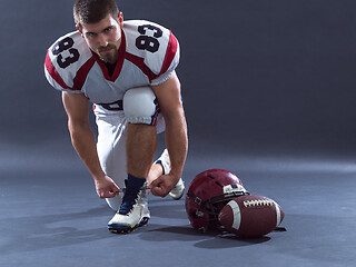 Image showing American Football Player tie his shoe laces isolated on gray