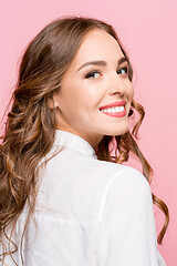 Image showing The happy business woman standing and smiling against pink background.