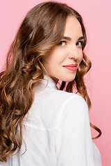 Image showing The happy business woman standing and smiling against pink background.