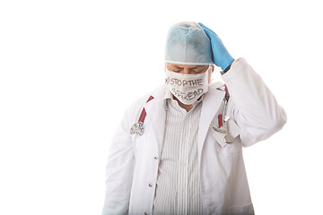 Image showing Anguished overworked doctor with head in hands during pandemic